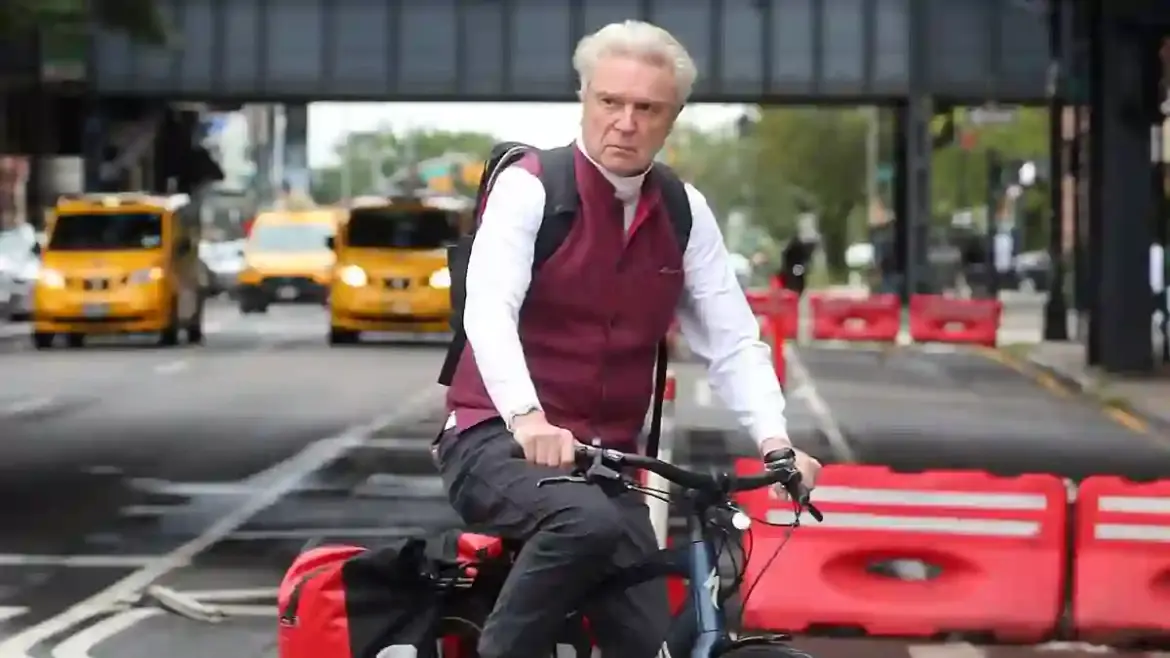 David Byrne rides through downtown New York on a mountain bike while promoting his first solo album in seven years