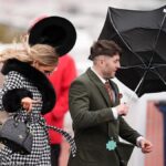 Revellers Brave Stormy Weather at Cheltenham Racecourse in Glamorous Outfits