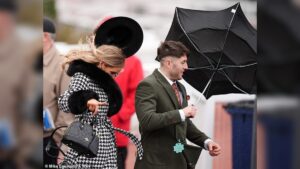Revellers Brave Stormy Weather at Cheltenham Racecourse in Glamorous Outfits