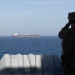 A U.S. Marine aboard the forward-deployed amphibious transport dock ship USS New Orleans (LPD 18) monitors shipping during U.S. maritime blockade operations