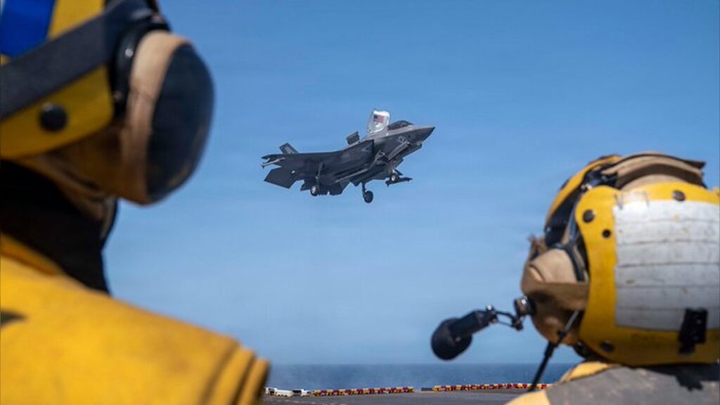 U.S. Sailors observe as a Marine Corps F-35B stealth fighter lands on the flight deck of USS Tripoli (LHA 7) while transiting the Arabian Sea