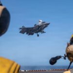 U.S. Sailors observe as a Marine Corps F-35B stealth fighter lands on the flight deck of USS Tripoli (LHA 7) while transiting the Arabian Sea